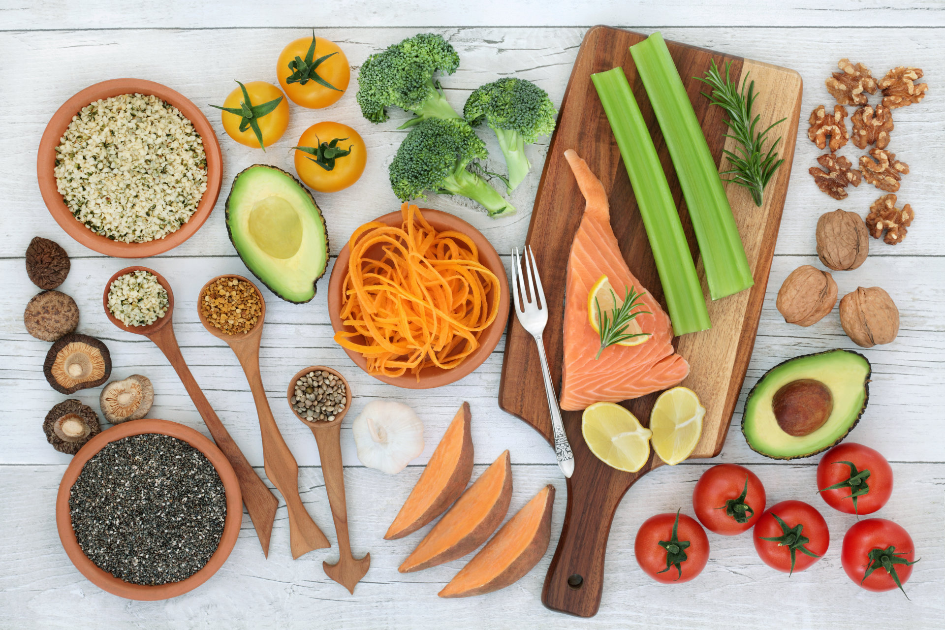 Top down shot of vegetables on a counter, with a wood cutting board and wooden bowls